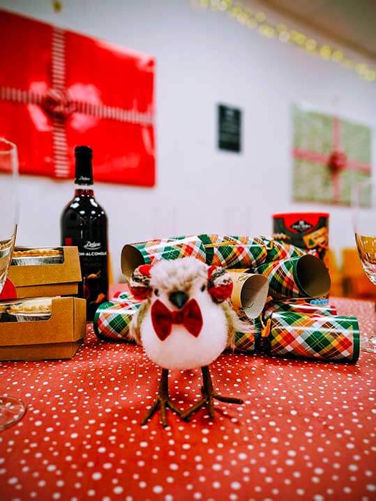 Christmas crackers on a table with a robin